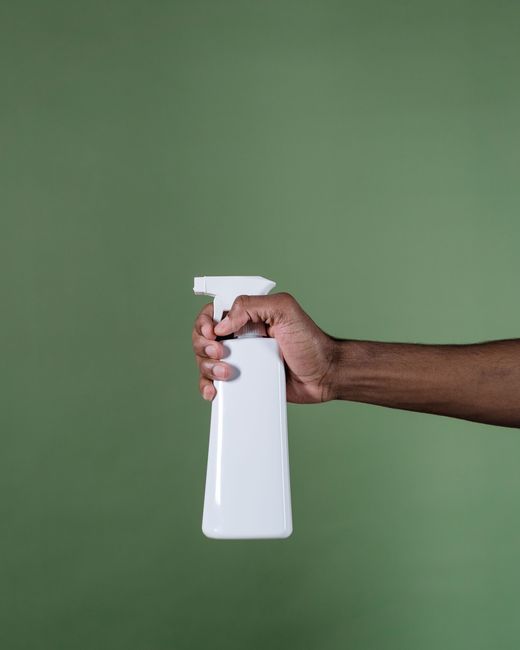 Main tenant un flacon vaporisateur blanc sur fond vert